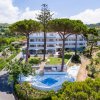 Edificio bianco a più piani circondato da alberi e giardini ben curati.