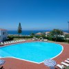 Una piscina all'aperto con lettini e ombrelloni, vista sul mare e un cielo limpido.