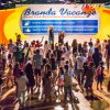 Persone ballano davanti a un palco giallo con l'insegna 