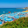 Spiaggia affollata con ombrelloni blu e bianchi e mare azzurro.