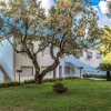 Edificio bianco con scale esterne, circondato da alberi e prato.