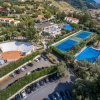 Veduta aerea di un complesso con campi da tennis, piscina e parcheggio.