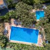 Due piscine circondate da alberi e lettini, viste dall'alto.