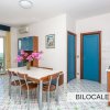 Un bilocale con cucina a vista, tavolo da pranzo e balcone con vista mare.
