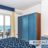 Camera da letto in un bilocale con armadio e letto matrimoniale, vista sul mare.