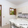 Cucina bianca con tavolo e sedie. Finestra aperta con vista su palme.