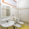 Bagno con lavabo, wc, bidet e dettagli in piastrelle colorate su pavimento giallo.