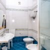 Bagno con lavabo doppio, wc, bidet, doccia, piastrelle blu e decorazioni.