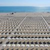 Spiaggia con file di ombrelloni bianchi.
