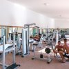 Una palestra luminosa con diverse macchine per esercizi e due persone che si allenano.