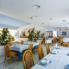 Ristorante elegante con tavoli apparecchiati, sedie di legno e piante decorative.