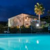 Edificio in pietra illuminato vicino a una piscina blu di sera.
