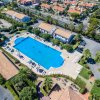 Vista aerea di una piscina rettangolare con lettini, circondata da edifici e strade.
