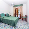 Camera d'albergo con letto matrimoniale, mobili verdi e tappeto colorato, finestra vista mare.