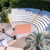 Anfiteatro all'aperto con gradinate e vegetazione intorno.