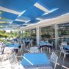 Veranda con tavoli e sedie, coperta da teli blu.