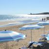 Spiaggia con ombrelloni azzurri e mare scintillante.