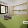 Camera con letto matrimoniale e borsa su letto verde.
