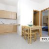 Cucina e soggiorno con tavolo e sedie in legno chiaro.
