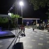 Spettacolo serale all'aperto con pubblico seduto.