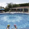 Piscina rotonda con bagnanti e ombrelloni blu.