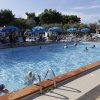 Piscina lunga con bagnanti e sdraio.