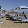 Spiaggia con lettini e ombrelloni blu.