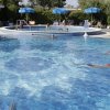 Piscina all'aperto con bagnanti e ombrelloni.