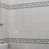 Bagno con piastrelle bianche, decorazioni blu e gialle, e finestra accanto a un bidet.