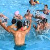 Persone che giocano e spruzzano acqua in una piscina.