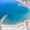 Veduta aerea di una spiaggia con ombrelloni e mare calmo.