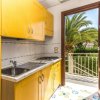 Cucina con mobili gialli e una porta aperta che dà su un balcone con palme.