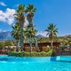 Piscina con palme al centro e montagne sullo sfondo.