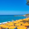 Spiaggia con ombrelloni gialli, persone in acqua e orizzonte azzurro.
