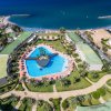 Vista aerea di un resort con piscina a forma di cuore, giardini e accesso al mare.