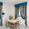 Sala con tavolo e sedie, tende blu e gialle, accesso a un balcone.