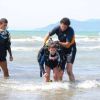 Due adulti aiutano un bambino in attrezzatura subacquea a uscire dall'acqua.