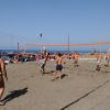 Persone giocano a beach volley sulla sabbia vicino al mare.