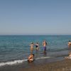 Persone giocano sulla riva del mare sotto un cielo limpido.
