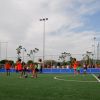 Bambini che giocano a calcio su un campo recintato, indossando pettorine rosse.