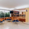 Sala con tavoli e sedie, finestrone con veduta di piante e TV a muro.