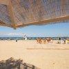 Spiaggia soleggiata con ombrelloni, mare e capannina in paglia.