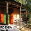 Veranda di una casa con sedie bianche, circondata da piante fiorite.