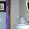 Bagno con tenda viola a pois, lavabo e specchio rotondo. Scritta 