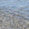 Acqua trasparente su ciottoli, con leggere increspature.