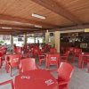 Una terrazza coperta con tavoli e sedie rosse di plastica.
