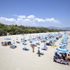Spiaggia con lettini e ombrelloni blu, persone che prendono il sole.