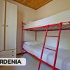 Letto a castello con struttura rossa in una stanza con armadio e soffitto in legno.