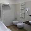 Bagno con vasca, sanitari moderni, rivestimenti chiari e un asciugacapelli a parete.