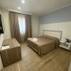 Camera d'albergo con letto matrimoniale, televisione e grandi tende marroni.